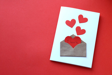 Valentine's day greeting card made with your own hands.Postcard with hearts and an envelope on a red background.Copy space.Beautiful holiday background. Declaration of love on February 14.