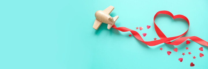 small wooden toy airplane lucky with red ribbon in the shape of heart
