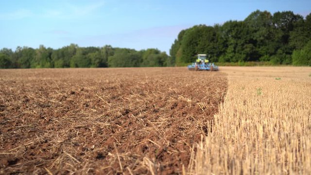 Blurred blue tractor discing stubble field soil with special equipment