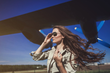 Portrait of a beautiful woman in Aviator glasses near aircraft