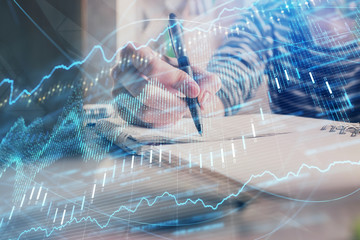 Financial forex graph drawn over hands taking notes background. Concept of research. Double exposure