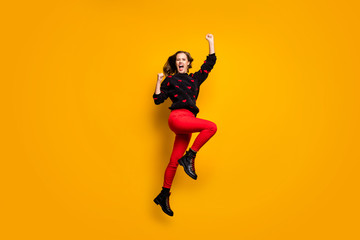 Fototapeta na wymiar Full length profile photo of funny lady jumping up high rejoicing raising fists wild football fan wear hearts pattern sweater red trousers footwear isolated yellow color background
