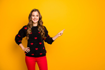 Photo of funny pretty lady indicating finger empty space advising amazing low shopping season prices wear hearts pattern pullover red pants isolated yellow color background