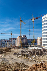 Construction site background. Hoisting cranes and new multi-storey buildings. Industrial...