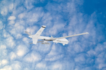 RC military drone flies against the backdrop of blue peaceful sky with white clouds