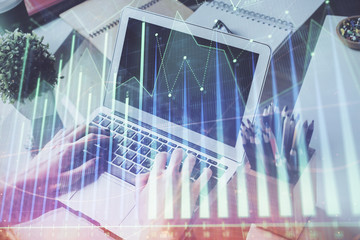 Double exposure of stock graph with businessman typing on computer in office on background. Concept of hard work.