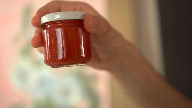Shaking a red tempera glass jar, close up high fps