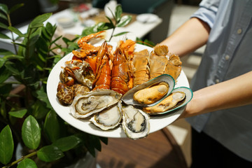 Plate of various types of seafood set, steamed rock lobster, baby lobster, New Zealand mussel, blue...
