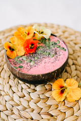 Fototapeta na wymiar healthy Breakfast in a plate of coconut with nasturtium flowers on natural wicker napkin