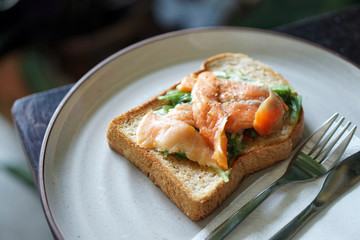 A plate of homemade smoked salmon and cream cheese toast served with japanese seaweed salad.
