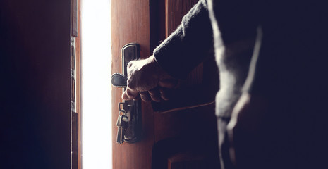 Fototapeta na wymiar Silhouette of an elderly man opening the door