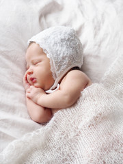 Newborn. Photoshoot of a newborn. Newborn girl sleeping in a white hat. Newborn baby on white.