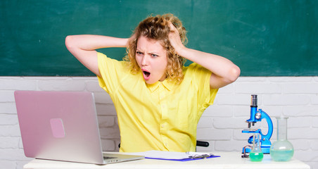 worried student with microscope and beaker. girl in classroom laboratory with computer. biology experiment. make notes about chemistry research results. scientist teacher at school lab. bad news