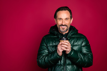 Photo of stylish trendy man smiling toothily holding cup of coffee disposable standing near empty space isolated vivid color background