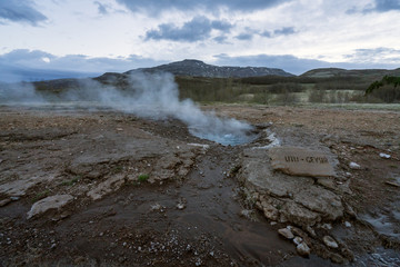 Litli-geysir or mini geysir next to Strokkur in Haukaalur area in the Icelandic countryside. Blue hour and cloudy sky with boiling hot pool infront. Travelin concept.