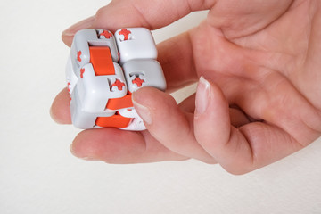 Colorful fingers antistress fidget cube toy in hand on white background. development of fine motor skills of fingers of children - obrazy, fototapety, plakaty