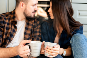 Happy couple sit on the floor with a cups