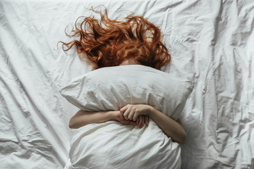 Red-haired little girl wakes up in the morning in her crib