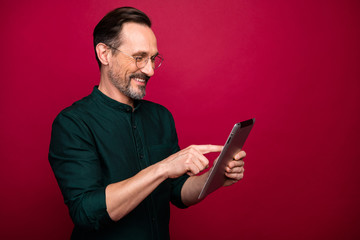 Turned photo of man browsing through modern gadget testing how different applications work on this device isolated red vivid color background