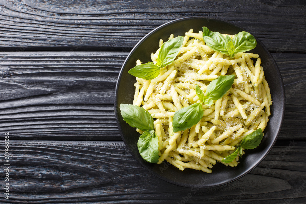 Wall mural Traditional trofie pasta with green basil pesto and parmesan cheese close-up in a plate. Horizontal top view