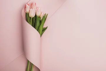Foto op Plexiglas Top view of tulip bouquet wrapped in paper swirl on pink background © LIGHTFIELD STUDIOS