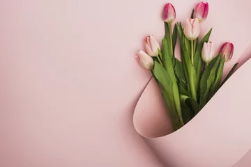 Fotobehang Top view of pink and purple tulips wrapped in paper swirl on pink background © LIGHTFIELD STUDIOS