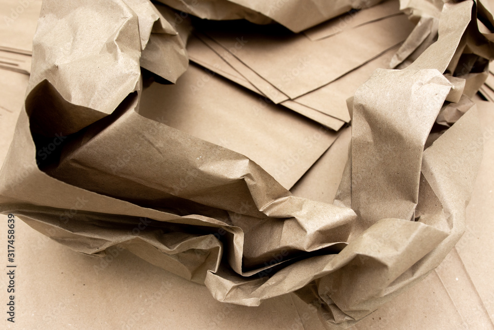 Wall mural crumpled sheets of craft paper on a background of brown packages. place for text