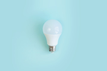one LED light E27 bulb on blue background. energy saving Eco power concept. minimalism. Flat lay. Innovative LED lighting solution. Copy space