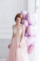 Fototapeta premium Beautiful woman holding pink balloons heart shaped. Model female on st. Valentine`s background.