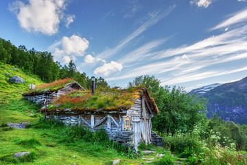 Typical norwegian old wooden houses with grass roofs near Sunnylvsfjorden fjord and famous Seven...