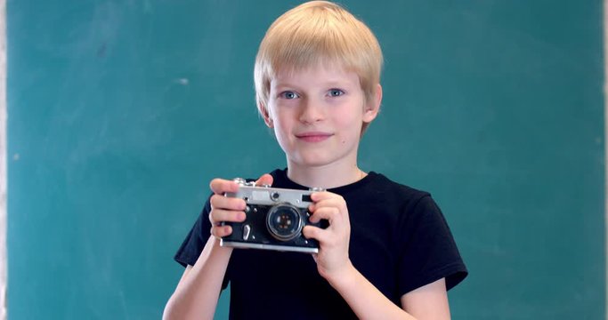 a blond boy with blue eyes cockes the camera shutter and takes a picture
