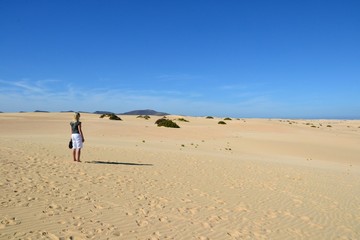 Obraz premium Unidentified woman standing on the sand dunes. Parque Natural de Corralejo at Fuerteventura, Canary Islands, Spain