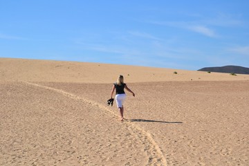 Fototapeta na wymiar Unidentified woman running through the sand dunes. Parque Natural de Corralejo at Fuerteventura, Canary Islands, Spain