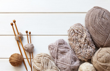 Needlework. Balls of wool yarn and wooden knitting needles on a white table. Hand knitting and...
