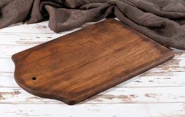 Cutting board over a towel on a wooden white kitchen table.