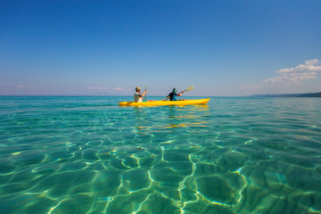 Father and son having fun during summer beach vacations. Happy family adventures concept. Boy and man kayaking together in sunny sea amazing clear water of Aegean sea in Greece. - obrazy, fototapety, plakaty