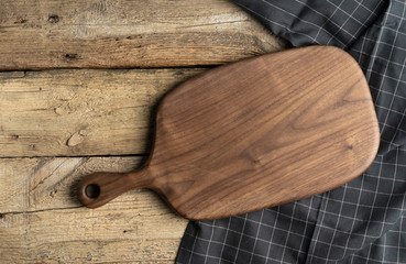 Cutting board over towel on wooden kitchen table. Top view