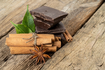 Pieces of chocolate and spices on wooden table