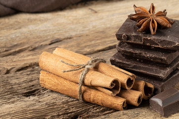 Pieces of chocolate and spices on wooden table