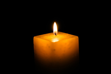 A lighted candle on a neutral black background, ideal for text application