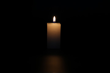A lighted candle on a neutral black background, ideal for text application