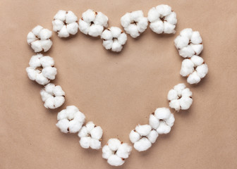 Heart shape made of cotton flowers on a natural paper background.