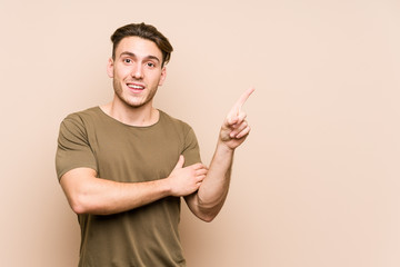 Young caucasian man posing isolated smiling cheerfully pointing with forefinger away.