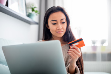 Asian girl making online payment using laptop for shopping at home