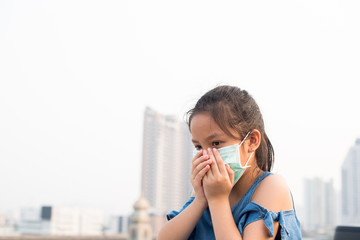 asian little child girl wearing a protection mask against PM 2.5 air pollution. sick girl with medical mask.  little girl using face mask to protect their health from pollution smog