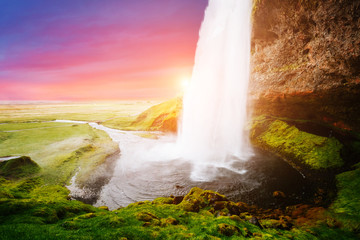 Stunning image of powerful Seljalandsfoss waterfall in sunlight.