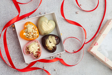 Orange, strawberry, matcha and dark chocolate heart shaped  bars in gift box with red ribbon 