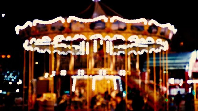Christmas carousel blurred video. Bright carousel with lights and horses rolls the children. The video is out of focus for background.