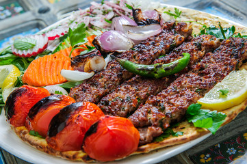 Healthy barbecue different meat with vegetables and sauce. served with a black plate. close up view on a light background. Arabic food.