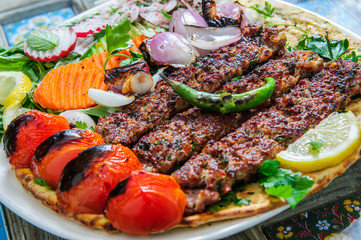 Healthy barbecue different meat with vegetables and sauce. served with a black plate. close up view on a light background. Arabic food.
